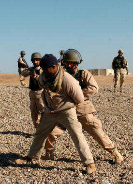 Police officers from the 3rd Public Order Battalion train on detaining prisoners at a makeshift check point at Forward
                                    Operating Base Seven in December. The officers were to begin policing the city of Samarra at the end of the month. They were
                                    being trained by military and civilian officials, include George Clark, an international police officer and Philadelphia resident
                                    who played the role of the detainee. (Photo by Spc. Ismail Turay Jr., 196th MPAD)